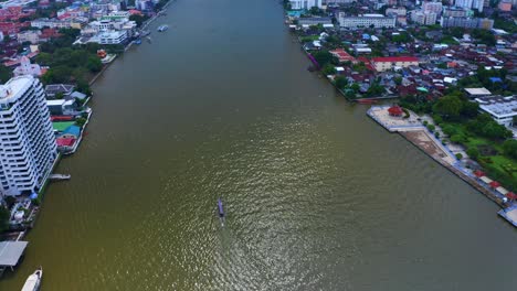 Aerial-View-Of-Long-Tailed-Boat-In-The-Canals-Of-Chao-Phraya-River-In-Bangkok,-Thailand