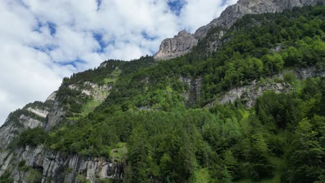 Low-angle-view-of-majestic-green-rocky-Alps-mountains-with-cloudy-sky-above
