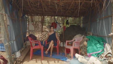 Cinematic-slow-motion-shot-of-an-Indian-fashion-model-sitting-in-a-plastic-chair-in-a-blue,-red-and-orange-sustainable-fashion-dress-in-Goa-India,-Slomo