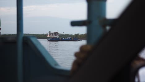 POV-shot:-A-cargo-ship-on-the-coastline-is-being-seen-from-another-ship-hiding-behind-the-grill