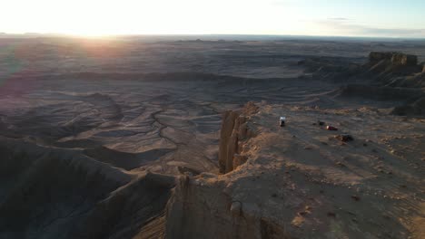 Luftaufnahme-Von-Fahrzeugen-Auf-Dem-Plateau-Mit-Atemberaubendem-Blick-Auf-Den-Sonnenuntergang-über-Der-Wüstenlandschaft,-Drohnenaufnahme