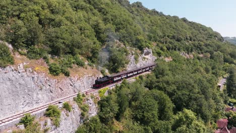 A-steam-train-moves-towards-the-camera,-followed-by-a-drone-tracking-the-locomotive,-Martel,-Lot,-France