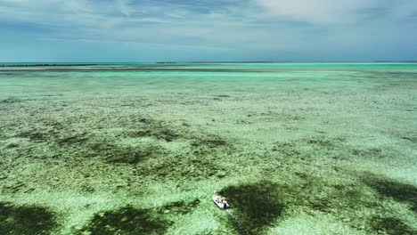 Slowly-Moving-Fishing-Boat-in-Flat-and-Reef,-Aerial-View-from-Behind,-Bahamas