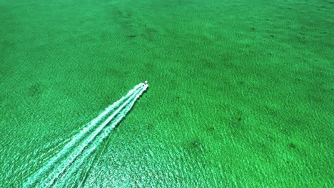 Top-Down-Aerial-View-of-Boat-Motoring-Away-in-Turquoise-Bahamas-Flat