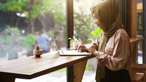 Eine-Aufstrebende-Asiatische-Muslimin,-Die-An-Einem-Strahlend-Sonnigen-Tag-Einen-Entspannten-Moment-Im-Café-Genießt