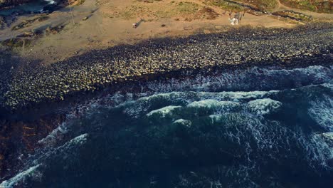 Drone's-backward-view-of-waves-crashing-on-the-beach