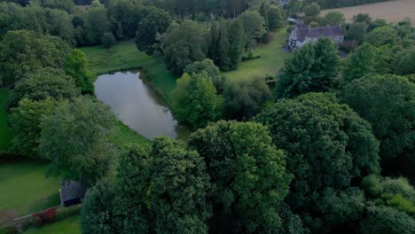 Aerial-drone-view-of-small-lake-in-lush-green-forest-of-Brittany-in-France