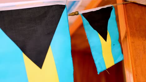 Bahamian-Flags-Fluttering-in-the-Wind,-Wood-Backdrop,-Patriotic-Display