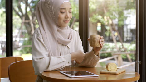 Eine-Aufstrebende-Asiatische-Muslimin,-Die-An-Einem-Strahlend-Sonnigen-Tag-Einen-Entspannten-Moment-Im-Café-Genießt