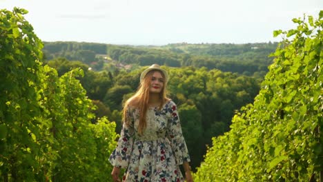 Stunning-HD-footage-of-a-young-white-Caucasian-woman-with-a-knitted-hat-in-a-dress-joyfully-walking-through-vineyards-and-admiring-the-surroundings