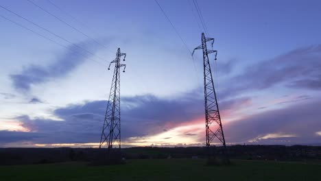 Cinematic-blue-hour-sky-time-lapse-of-clouds-and-sunset-glow-behind-utility-towers