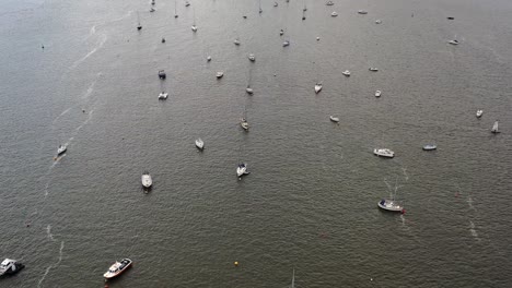 Aerial-drone-shot-looking-down-and-moving-forward-along-the-River-Exe-Estuary,-showing-moored-up-boats-and-shimmering-water,-in-Devon,-UK