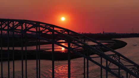 Silhouette-Bogenbrücke-über-Den-Fluss-Bei-Sonnenuntergang-Mit-Orangefarbenem-Himmel