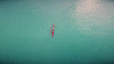 Drohnenvideo-Eines-Sportkajaks,-Der-An-Einem-Schönen-Und-Heißen-Tag-In-Thailand-Durch-Einen-Großen-See-In-Richtung-Eines-Großen-Bootes-Paddelt