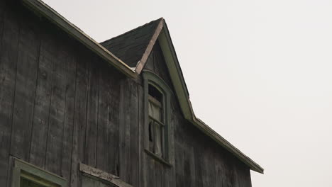 Wind-Weht-Zerrissener-Vorhang,-Der-Das-Holzfenster-Eines-Verlassenen-Hauses-Bedeckt,-Mittelgroß
