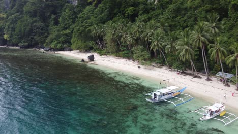 Aerial-trucking-pan-across-double-outrigger-canoes-beached-on-pasandigan-cove