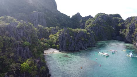 Aerial-pullback-reveals-stunning-cove-with-double-outrigger-canoes-secluded-in-el-nido-philippines