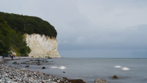German-People-and-Tourists-Walk-Along-White-Chalk-Cliffs-on-Rugen-Island,-Traveling-on-Pebble-Beach-by-Baltic-Sea---timelapse-motion