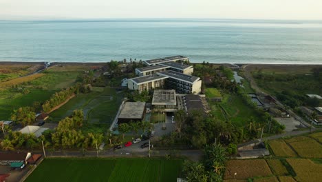 Oceanfront-Wyndham-Tamansari-Jivva-Resort-Bali-With-Scenic-Sunset-Ocean-View-and-Farmlands-Surroundings-in-Klungkung-Bali,-Indonesia---Aerial-Orbiting