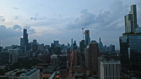 Aerial-view-flying-in-front-of-the-South-Loop-cityscape,-cloudy-dusk-in-Chicago,-USA