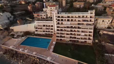 Luftaufnahmen,-Die-Vom-Fenster-Des-Resorts-Aus-Rückwärts-Fliegen-Und-Den-Strand-Von-Batroun-Bei-Sonnenuntergang-Im-Libanon-Freigeben