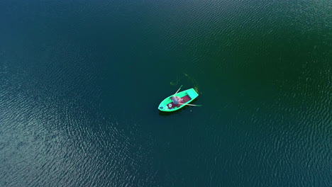 A-person-fishing-from-a-rowboat-on-a-huge-lake---pullback-aerial