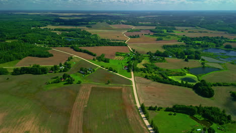 Aerial-drone-pullback-from-y-shaped-intersection-of-dirt-roads-above-farmland-fields