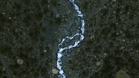 Aerial-top-down-view-of-water-stream-flowing-on-dry-mountain-river-bed-in-Alpe-Ventina-of-Valmalenco-in-Northern-Italy