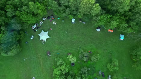 Campers-gather-in-a-forest-meadow-for-outdoor-leisure---straight-down-aerial-view