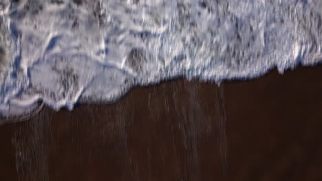 Die-Kamera-Einer-Drohne,-Die-Von-Einem-Sandstrand-Aus-Fliegt,-Zeigt-Die-Stürmischen-Wellen-Des-Ozeans