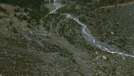 Flying-over-water-stream-flowing-on-dry-mountain-river-bed-of-Valmalenco-in-Northern-Italy
