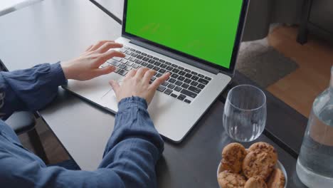Over-the-shoulder-shot-of-a-woman-typing-on-a-computer-laptop-with-a-key-green-screen
