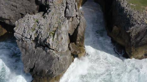 Slow-motion-waves-crashing-on-Bufones-de-pria-asturias-spain-cliff-side,-Aerial-trucking-pan-tilt-up