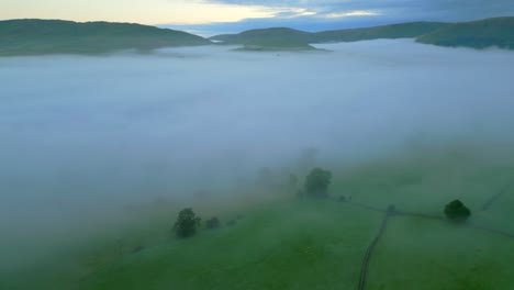 Flying-along-edge-of-fog-bank-over-countryside-with-hills-in-distance-at-sunrise