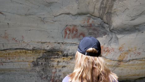 Women-immersing-herself-in-the-spectacular-display-of-Aboriginal-rock-art-created-on-ancient-cave-walls-of-Australia