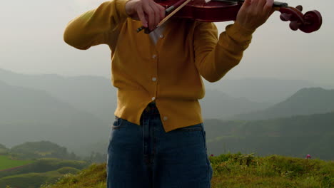 camera-moves-up-to-show-a-woman-playing-a-violin-with-her-eyes-closed-on-a-magical-misty-mountain