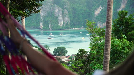 OTS-shot-of-person-swinging-in-hammock,-looking-at-coastline-of-Phi-Phi-Islands