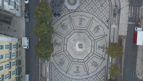 Aerial-shot-captures-the-scenic-Camões-Square-in-Chiado,-Lisbon,-Portugal,-showcasing-its-architectural-charm-and-the-vibrant-ambiance-of-the-area