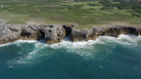 Rocky-limestone-seacliffs-eroded-away,-blue-water-of-bufones-de-pria-asturias-spain,-aerial