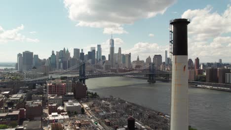 Manhattan-with-industrial-smokestack-and-generating-station-in-foreground,-4K-aerial