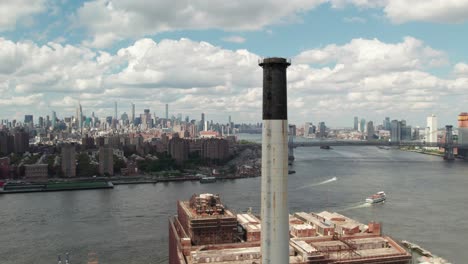 360-aerial-of-an-industrial-smokestack-in-Brooklyn-New-York,-city-skyline,-4K