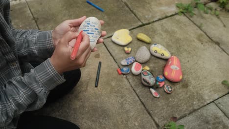 Female-hands-drawing-colorful-shapes-on-stones,-with-markers