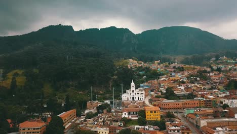 Drone-view-of-one-of-the-streets-of-the-centre-of-Bogotá,-Colombia,-with-colonial-houses-and-mount-Monserrate-in-the-background