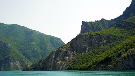 Albania,-Lake-Koman,-view-of-the-green-slopes-of-beautiful-mountains-amidst-emerald-waters