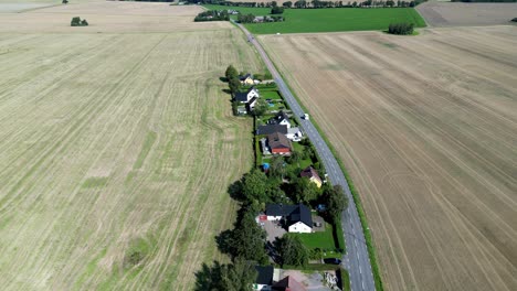Rural-fields-and-houses-as-a-car-drives-pass-in-Hässlunda-near-Mörarp-in-Skåne,-Sweden