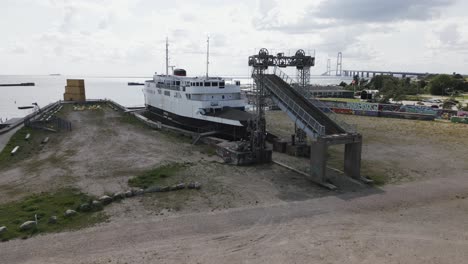 Altes-Boot-Im-Hafen-In-Der-Nähe-Einer-Großen-Brücke-über-Das-Meer