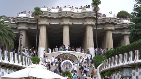Tilt-up-frontal-view-of-tourists-visiting-and-taking-photos-of-the-famous-Park-Guell-in-Barcelona,-Spain