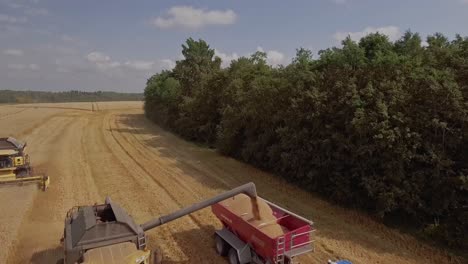 Aerial-view-of-a-combine-harvester-unloading-wheat-onto-a-tractor-trailer-on-a-wheat-field