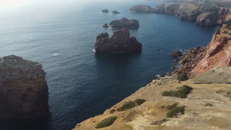 Orbiting-shot-of-Rocky-coastline-with-massive-cliffs-by-the-atlantic-ocean,-Algarve
