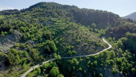 Aerial-view-showing-car-on-road-in-green-mountains-of-Rhodope-during-sunny-day-in-Bulgaria